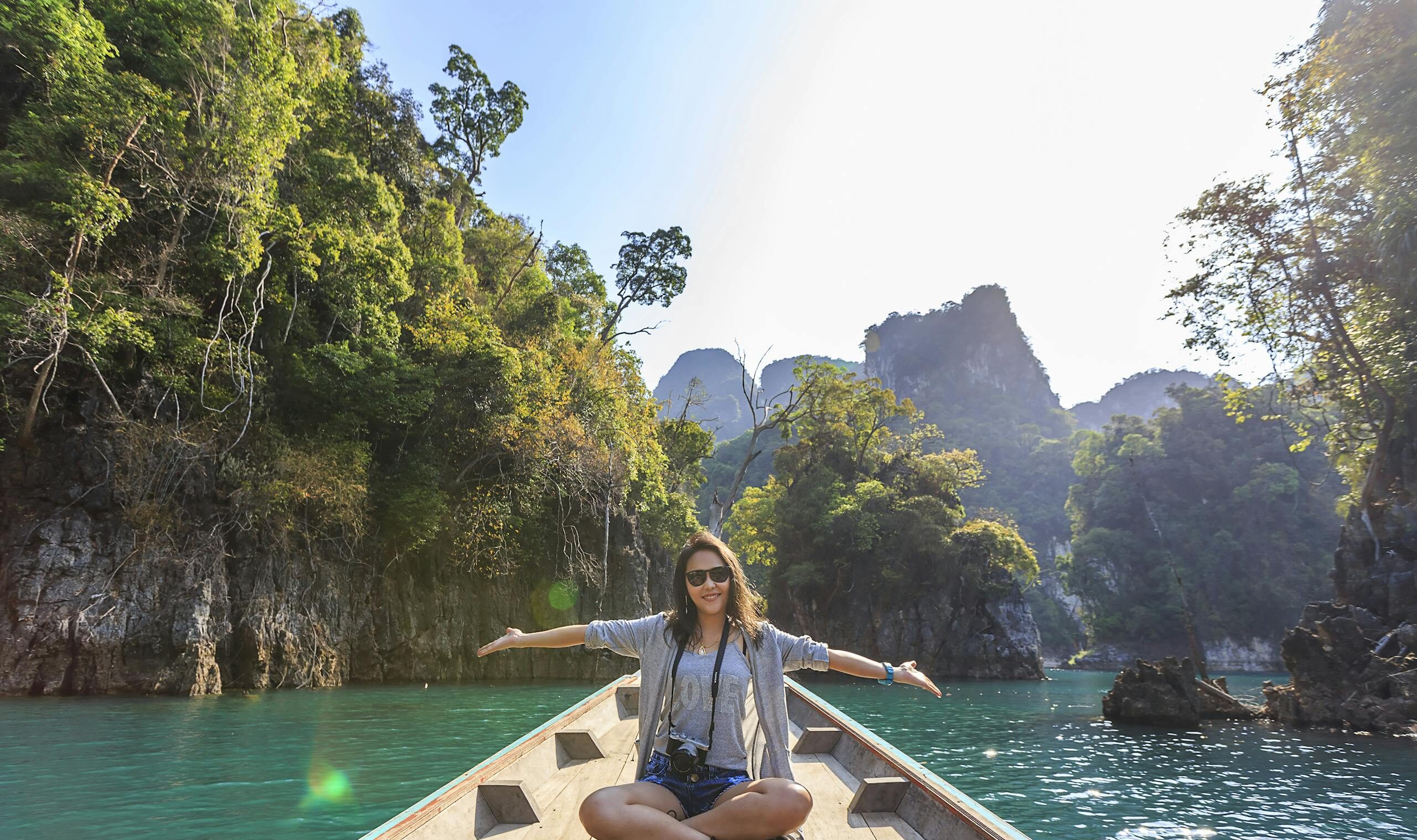 Asian woman relishing a serene boat journey through the lush karst landscape of Thailand's Khlong Sok.
