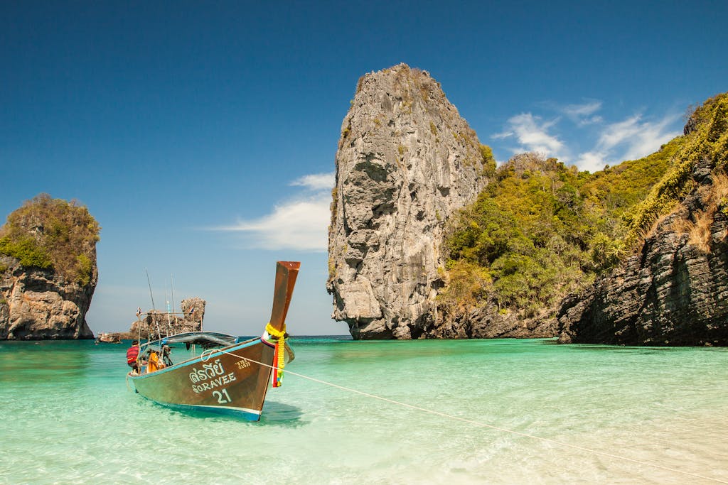 A picturesque tropical beach with a traditional boat and stunning limestone cliffs in clear turquoise waters.
