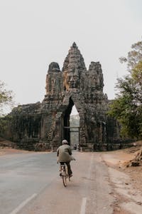 A cyclist rides a bicycle through the iconic South Gate of Angkor Thom in Cambodia.