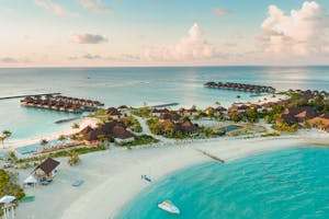 Stunning aerial view of a luxurious tropical resort in the Maldives, showcasing overwater bungalows and turquoise waters.